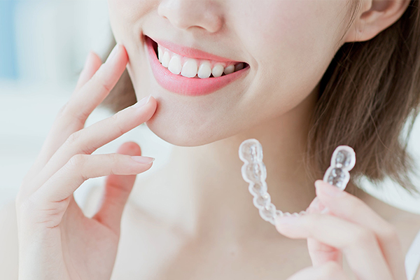A woman smiling and holding a toothbrush to her teeth, with a close-up view of her face.