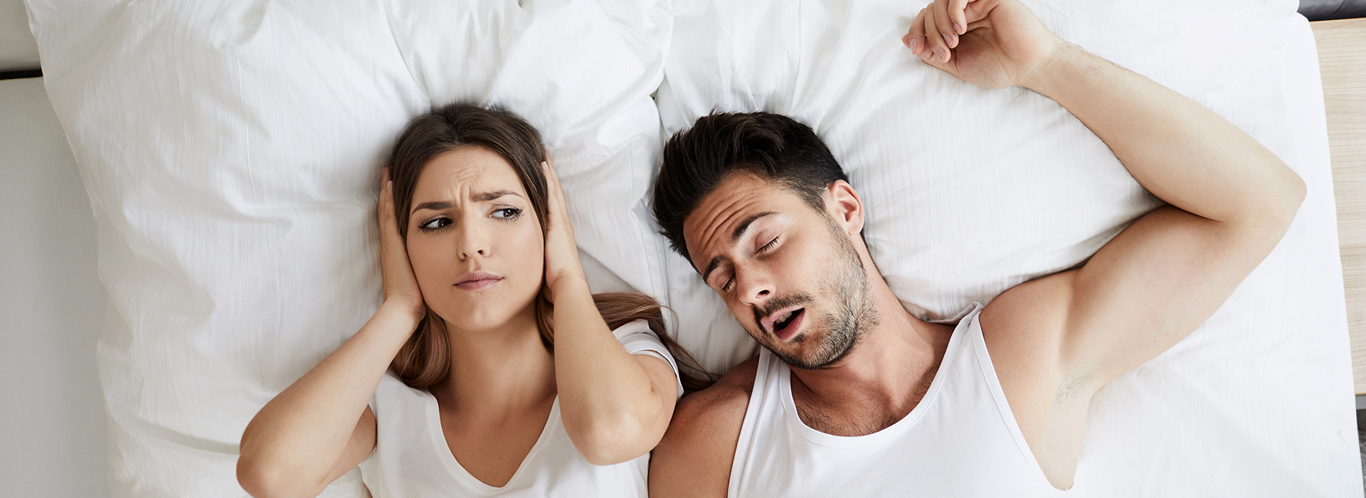 A couple lying in bed, with the man resting his head on the woman s shoulder.