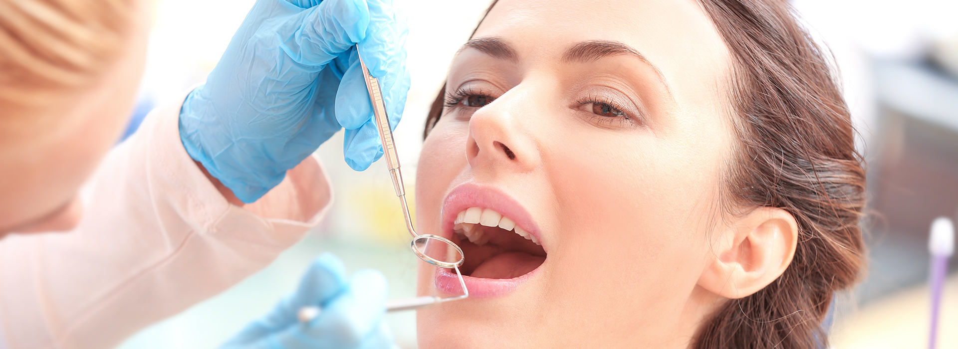A woman receiving dental care, with a dental hygienist performing a cleaning procedure.
