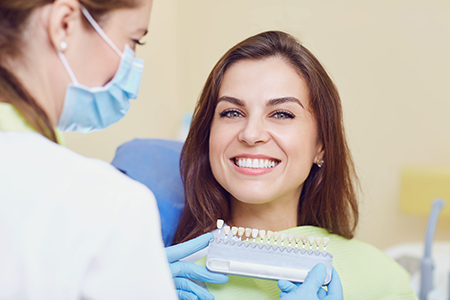 A dental professional assisting a patient with a smile during a teeth cleaning appointment.