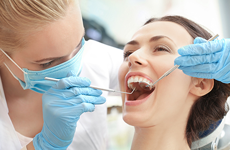 A dental hygienist performing a cleaning procedure on a patient s teeth, with the patient sitting in a dental chair and wearing protective eyewear.