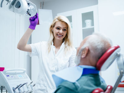 A dental professional assisting a patient in a dental chair.